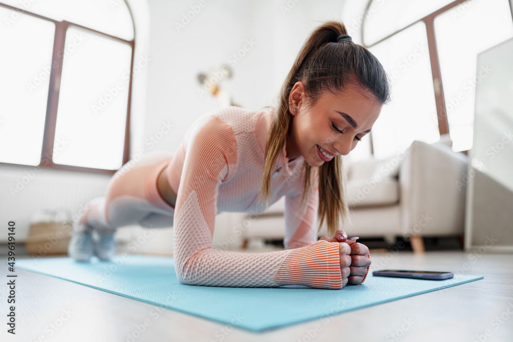 Obraz premium Sporty young woman doing plank exercise indoors at home