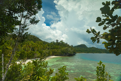 Huge storm clouds loom over the green landscape of beaches and rainforests, on the island of Gam, in Raja Ampat, West Papua, Indonesia photo