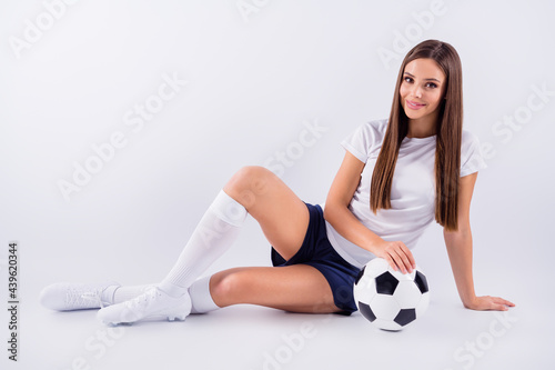 Portrait of her she nice-looking attractive lovely pretty cheerful cheery straight-haired girl sitting with ball enjoying hobby isolated on light white gray pastel color background