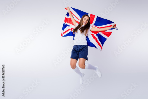 Full length photo positive energetic girl football fan enjoy support national team world cup championship scream jump hold uk flag wear t-shirt shorts socks boots isolated grey color background photo