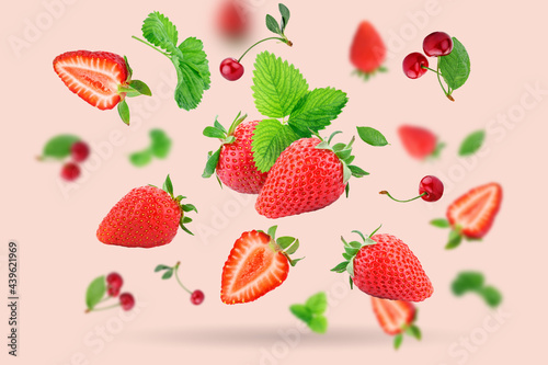 Strawberry berries and cherry berries levitating on a pink background. Horizontal. Selective focus.