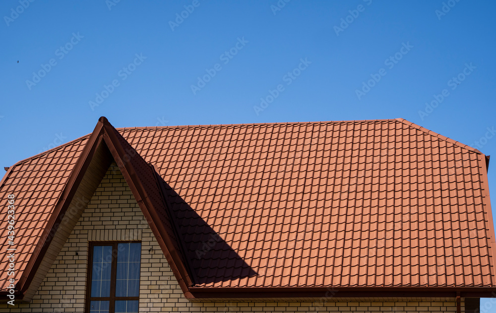 Red corrugated metal profile roof installed on a modern house. The roof of corrugated sheet. Roofing of metal profile wavy shape. Modern roof made of metal. Metal roofing. Red corrugated metal profile roof installed on a modern house. The roof of corrugated sheet. Roofing of metal profile wavy shape. Modern roof made of metal. Metal roofing.