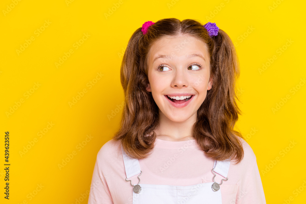 Photo portrait smiling amazed happy schoolgirl with tails looking copyspace isolated bright yellow color background Photo portrait smiling amazed happy schoolgirl with tails looking copyspace isolated bright yellow color background