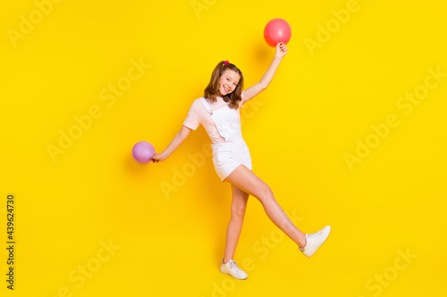 Full length body size view of pretty cheerful girl holding air balls dancing havin fun free time isolated over bright yellow color background photo