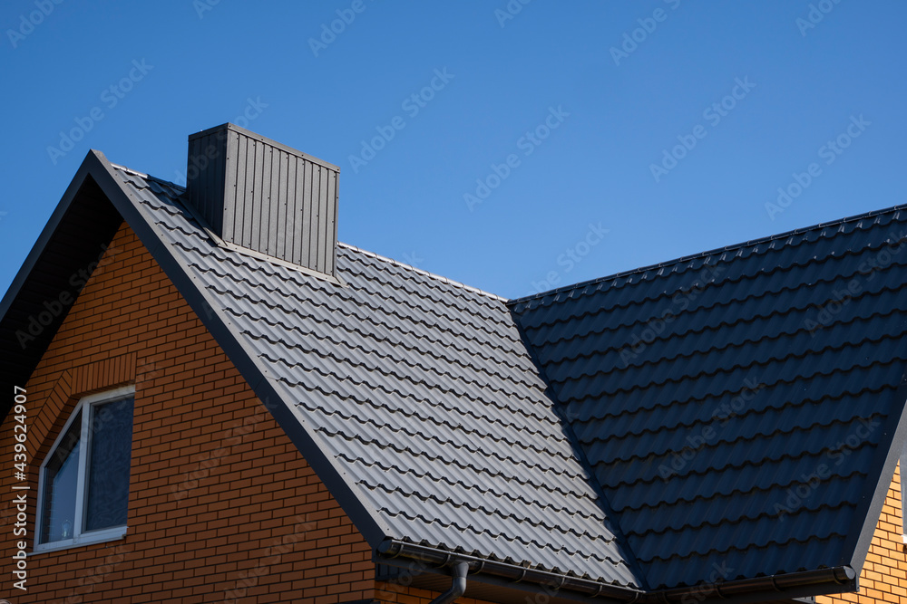 Grey corrugated metal profile roof installed on a modern house. The roof of corrugated sheet. Roofing of metal profile wavy shape. Modern roof made of metal. Metal roofing. Grey corrugated metal profile roof installed on a modern house. The roof of corrugated sheet. Roofing of metal profile wavy shape. Modern roof made of metal. Metal roofing.