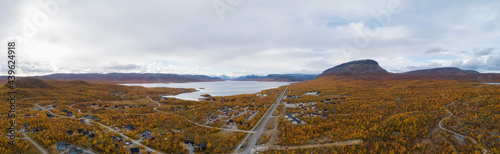 Aerial view of the road and village Kilpisjarvi in mountain valley at autumn. Saana mountain. Trees with red, yellow and orange leaves. Lapland. photo