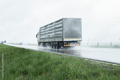 The movement of trucks of trucks with a semi-trailer and cars on a wet road in rain and fog and in poor visibility. Road safety concept. Copy space for text photo