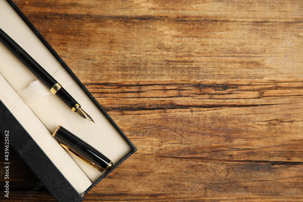 Beautiful fountain pen in box on wooden table, top view. Space for text