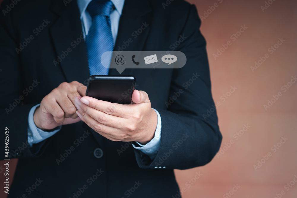Hands of a businessman using a smartphone with the icon images while standing with a brown background. Close-up photo. Communication, technology, and business customer support concept Hands of a businessman using a smartphone with the icon images while standing with a brown background. Close-up photo. Communication, technology, and business customer support concept