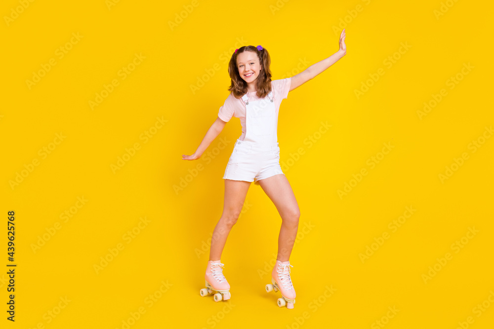 Full length body size view of attractive cheerful girl riding rollers having fun isolated over bright yellow color background