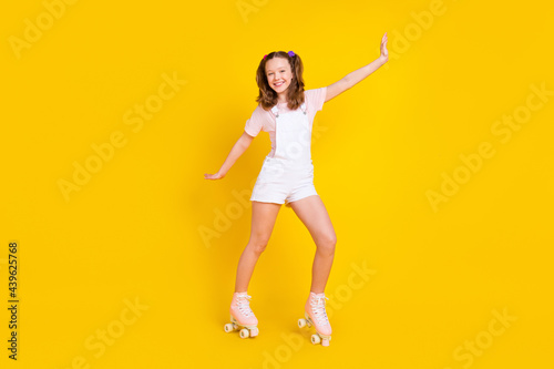 Full length body size view of attractive cheerful girl riding rollers having fun isolated over bright yellow color background