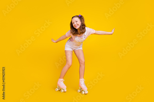 Full length body size photo schoolgirl riding rollers in summer isolated bright yellow color background photo