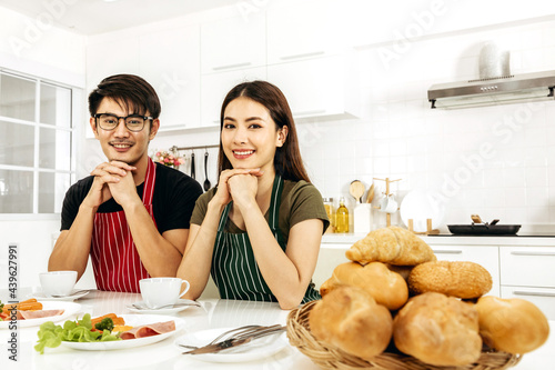Asian young couple smiling happily with drinking coffee enjoys together in kitchen room, activity lifestyle modern holiday and relationship family concept.
