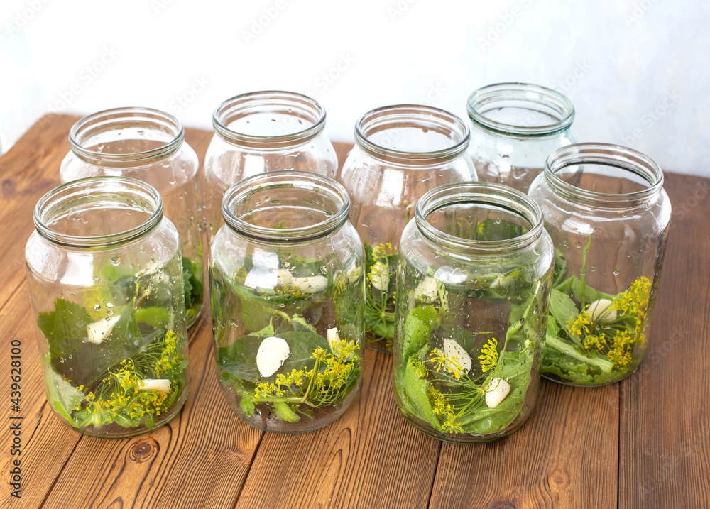 Jars with spices, garlic and pickle for preserving cucumbers. Jars with spices on a wooden background, preservation for the winter Jars with spices, garlic and pickle for preserving cucumbers. Jars with spices on a wooden background, preservation for the winter