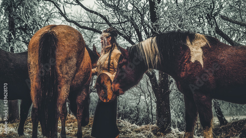 Shaman woman in winter landscape with her horse. © jozefklopacka