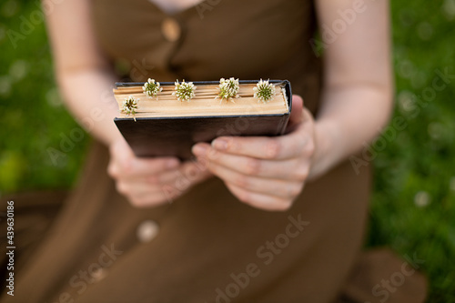 a girl in an olive dress holds a book with flowers in her hands. the summer vacation concept