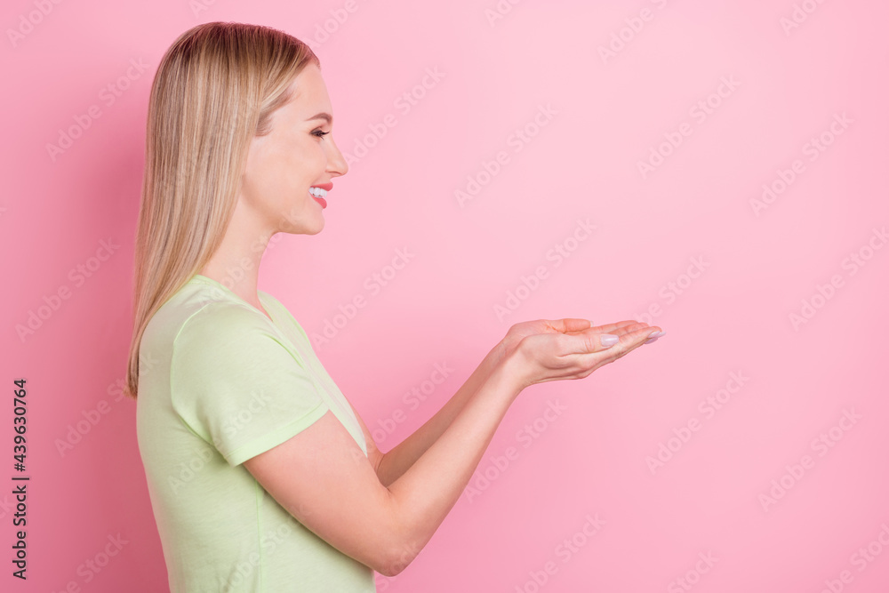 Profile photo of cheerful lady hand hold empty space toothy smile wear green t-shirt isolated on pink background Profile photo of cheerful lady hand hold empty space toothy smile wear green t-shirt isolated on pink background