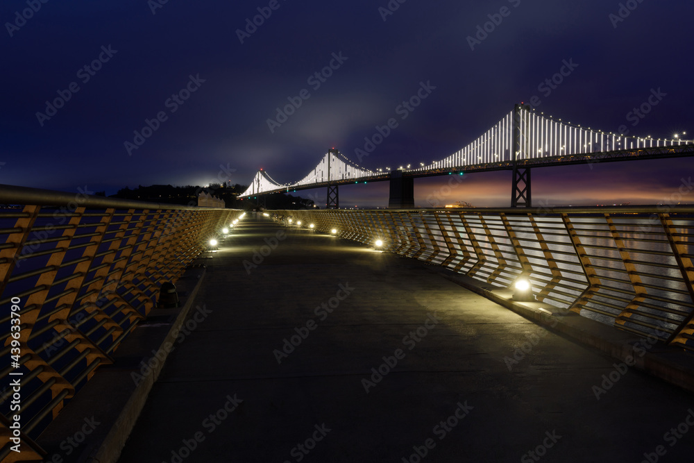 The Bay Bridge with Foggy Blue Skies framed by Pier 14 Railings. San Francisco, California, USA.