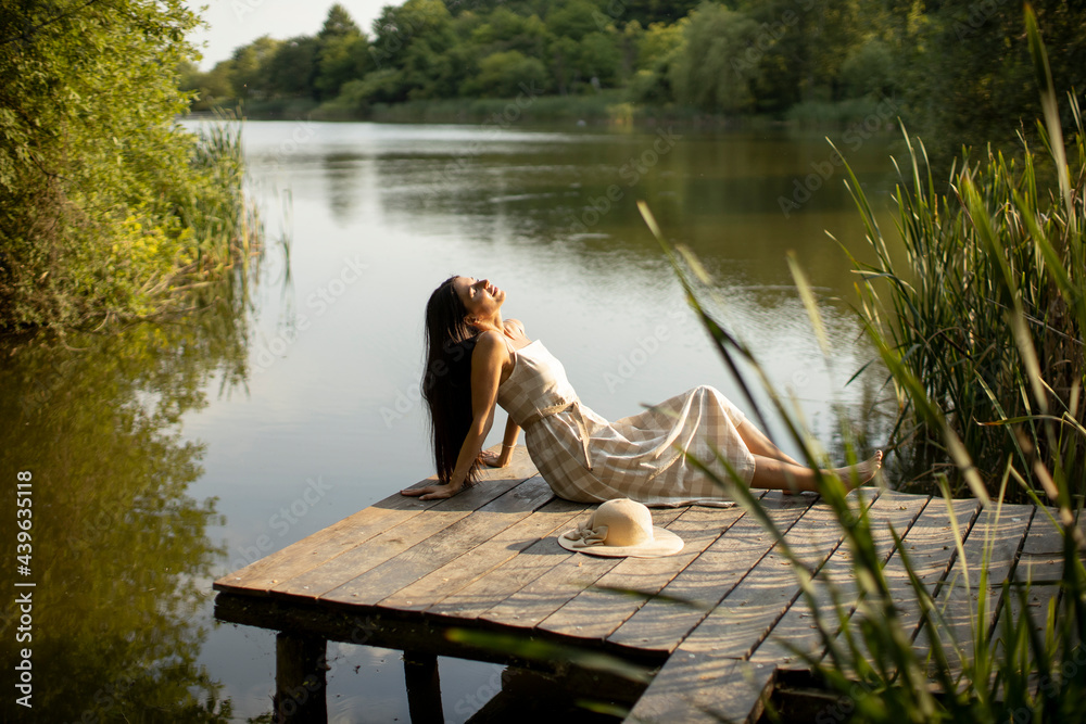 Relaxing young woman on wooden pier at the lake Relaxing young woman on wooden pier at the lake