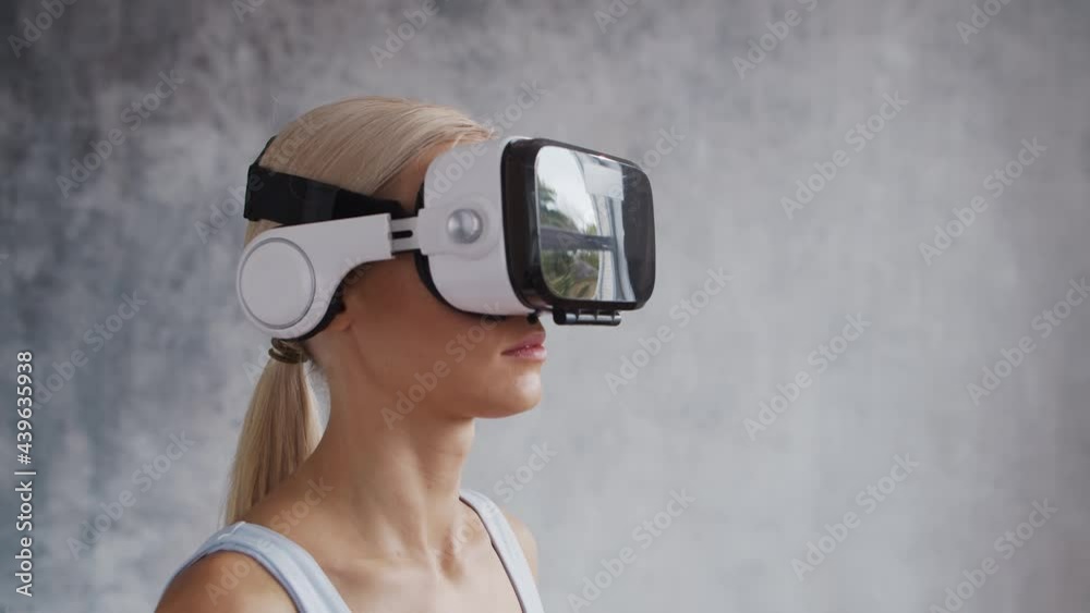 Young and sporty girl in sportswear is doing exercises at home using virtual reality helmet. Fit and slender blond woman goes in for sports and fitness. Healthcare, fat burn and wellness. Young and sporty girl in sportswear is doing exercises at home using virtual reality helmet. Fit and slender blond woman goes in for sports and fitness. Healthcare, fat burn and wellness.