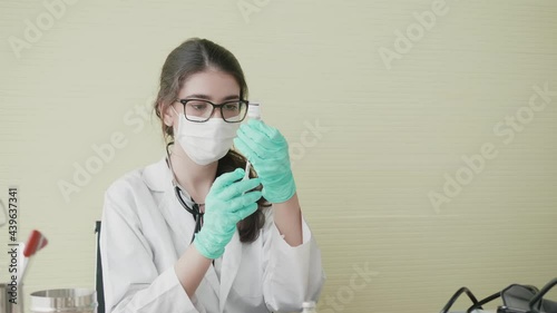 Cinematic shot of Female doctor wearing a mask filling syringes with vaccines Close-up of a researcher wearing a mask containing a syringe with a vaccine covid-19. Concept of facing the epidemic	 photo