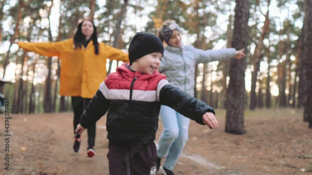 Happy family concept. Cute little boy running first. Happy children and mother playing together outdoor enjoy beautiful sunset in the pine forest. Teamwork and friendly family. Happy family concept. Cute little boy running first. Happy children and mother playing together outdoor enjoy beautiful sunset in the pine forest. Teamwork and friendly family.