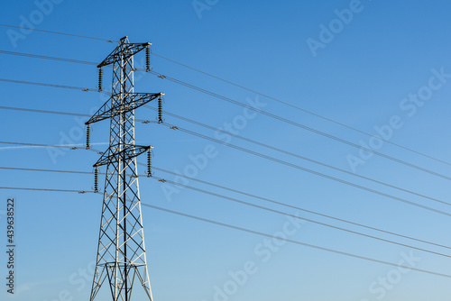 Electricity pylon tower with cables over blue sky landscape