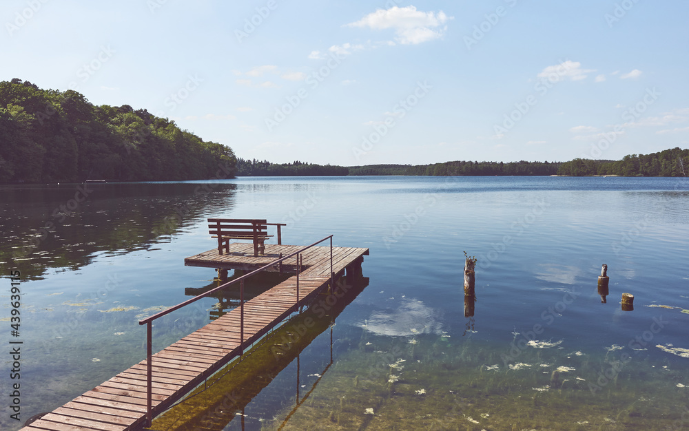 Wooden fishing and recreation platform at Lipie Lake on a sunny day, color toning applied, Poland.