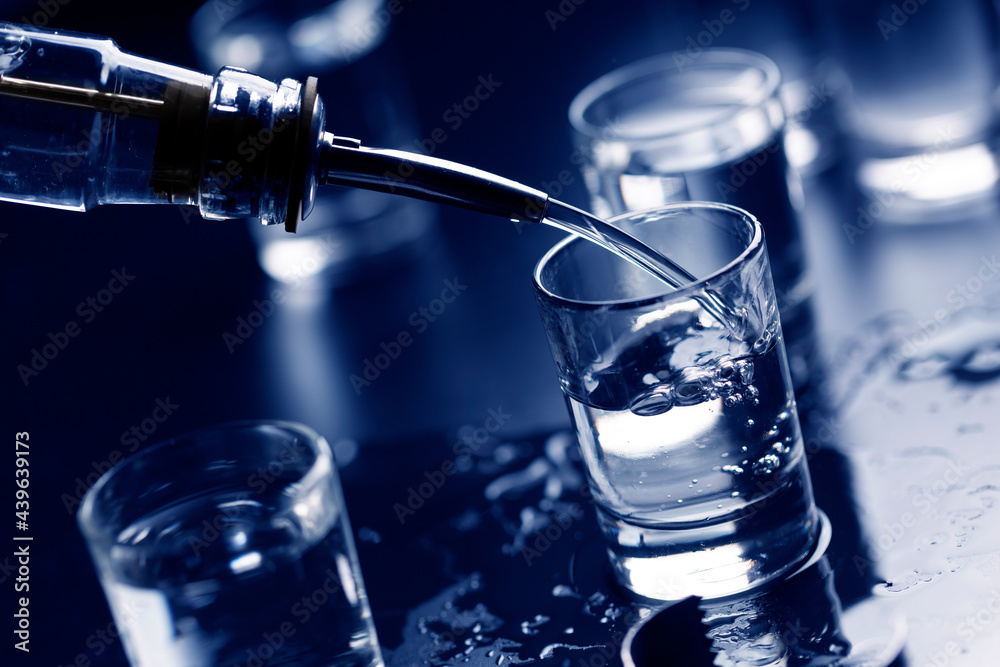 Russian vodka pouring from the bottle into glass in a bar.Copy space. Russian vodka pouring from the bottle into glass in a bar.Copy space.