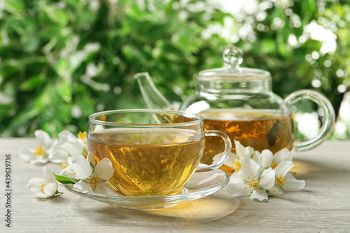 Aromatic jasmine tea and fresh flowers on wooden table