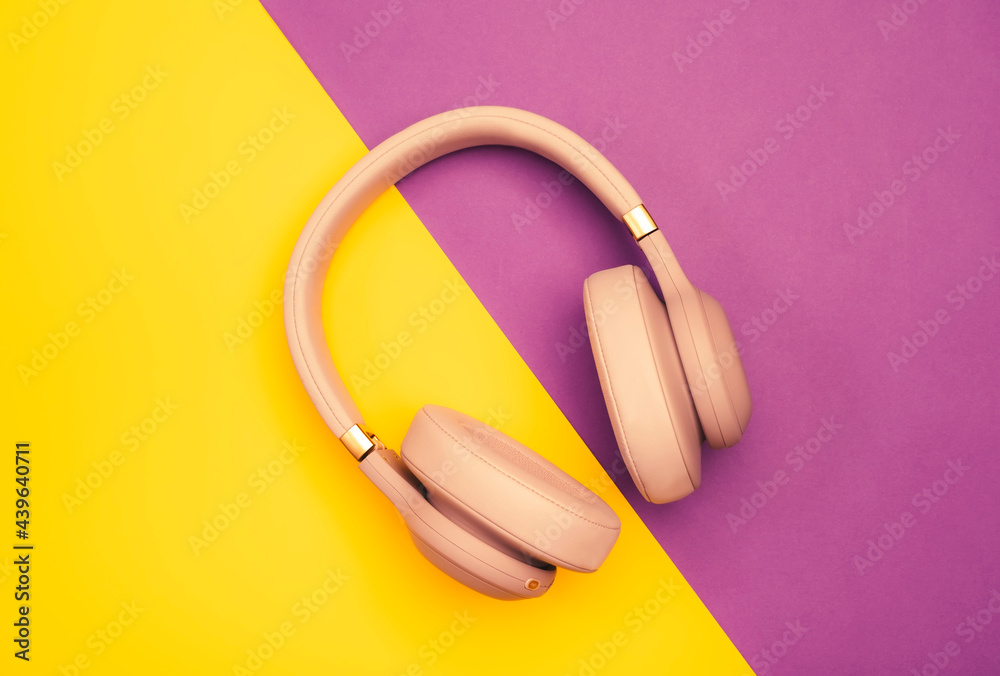 Pink Wireless Headphones on yellow purple background. Trendy minimal style. Music concept. Flat lay banner with copy space, top view