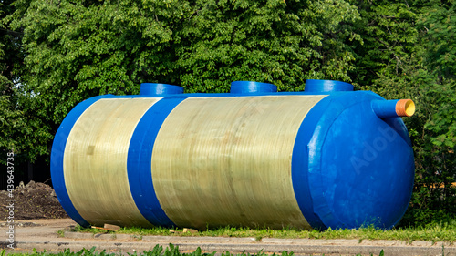 a huge blue container for collecting sewage waste lies on the grass