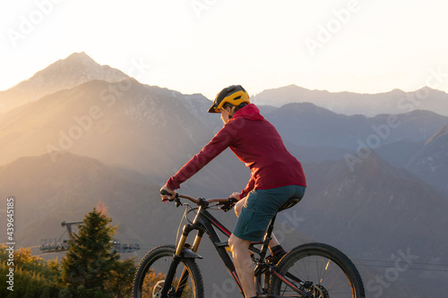 Woman riding mountain bike into the sunset. Beautiful golden summer light.