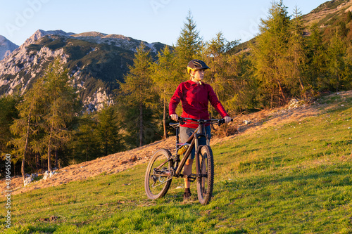 Woman walking uphill with mountain bike in nature on a beautiful day.