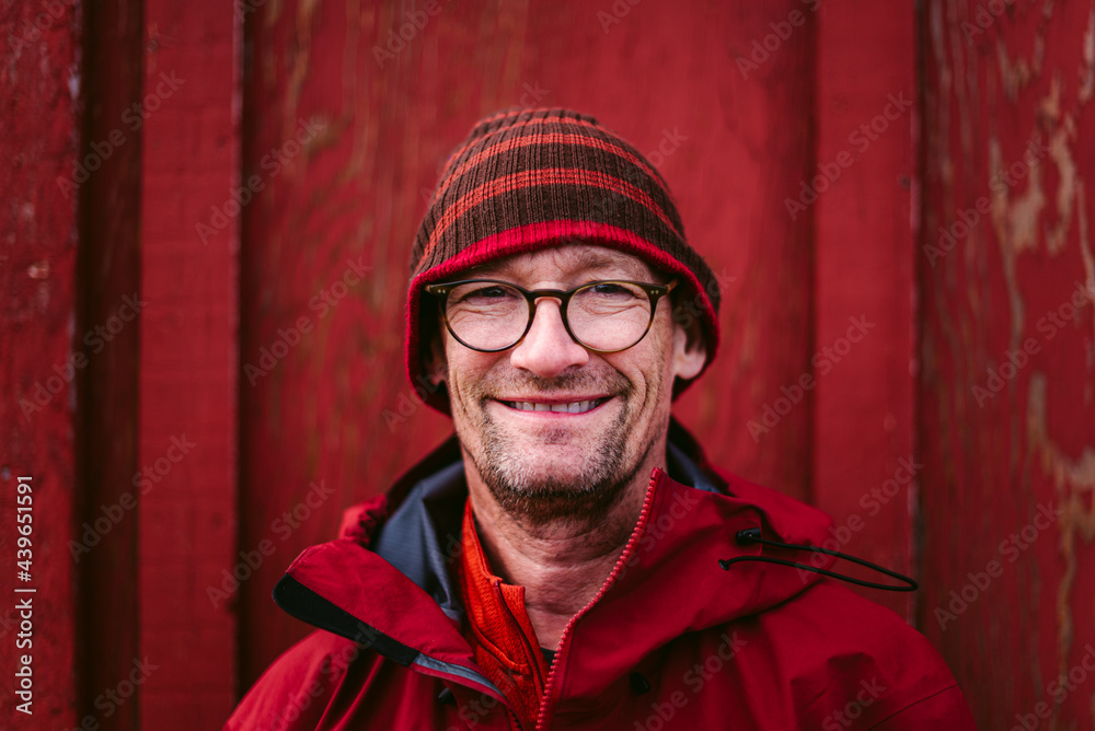 Cheerful adult man in warm jacket standing against red wall
Cheerful adult man in warm jacket standing against red wall