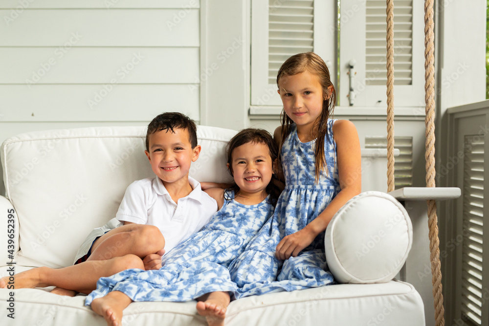Little Brother and Sisters Sitting on Porch Swing Little Brother and Sisters Sitting on Porch Swing