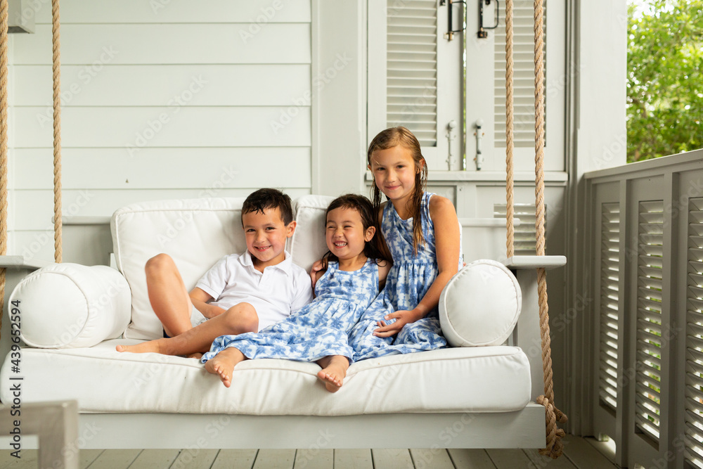 Little Brother and Sisters Sitting on Porch Swing