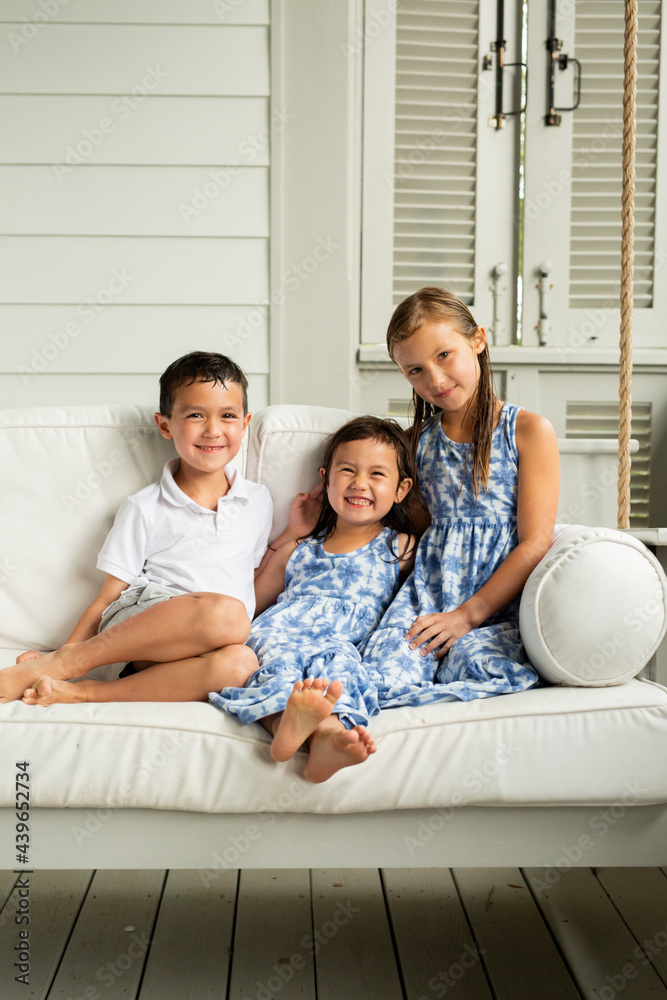 Little Brother and Sisters Sitting on Porch Swing Little Brother and Sisters Sitting on Porch Swing