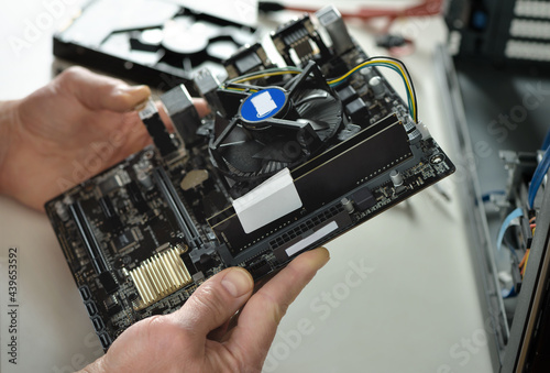 A technician is holding the motherboard in a desktop case.