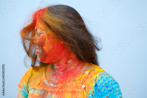 Young woman playing with her hair full of color powder during holi celebration photo