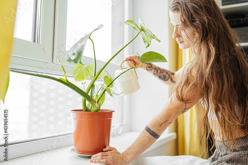 Young woman watering plant at home