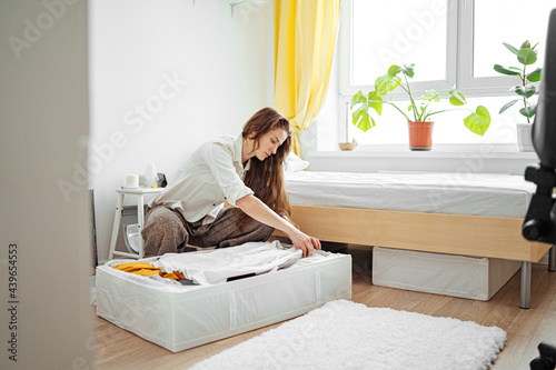 young woman packing clothes in a bedside box