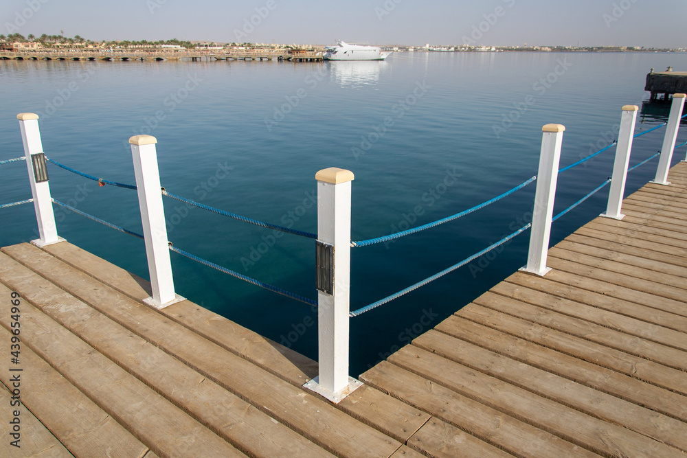 Travel. Pier on the sea. View at the sea from the wooden pier with posts and ropes with sparkling sea water