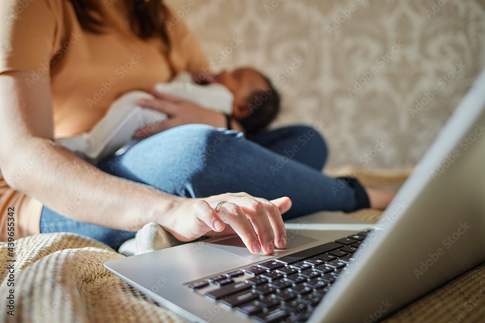 Mother multi-tasking, holding baby infant and using computer laptop at home. Mother multi-tasking, holding baby infant and using computer laptop at home.
