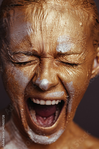 Woman with painted face screaming in studio
 photo