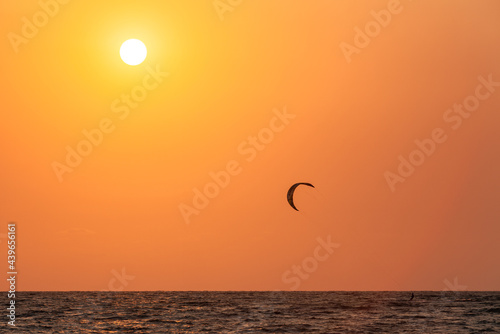 athlete kitesurfing in the sea against the background of an orange sunset