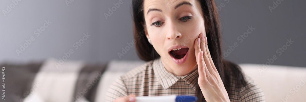 Young woman looking at pregnancy test in surprise Young woman looking at pregnancy test in surprise