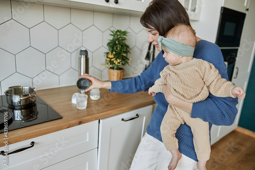 Mother pouring water into bottle to prepare milk