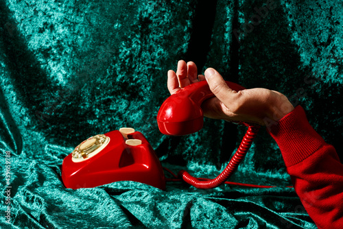holding the handset of a red telephone photo
