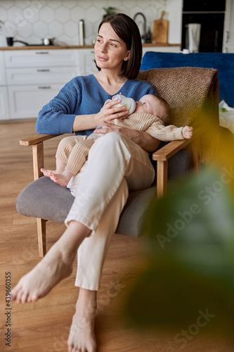 Mother feeding newborn baby from bottle with milk